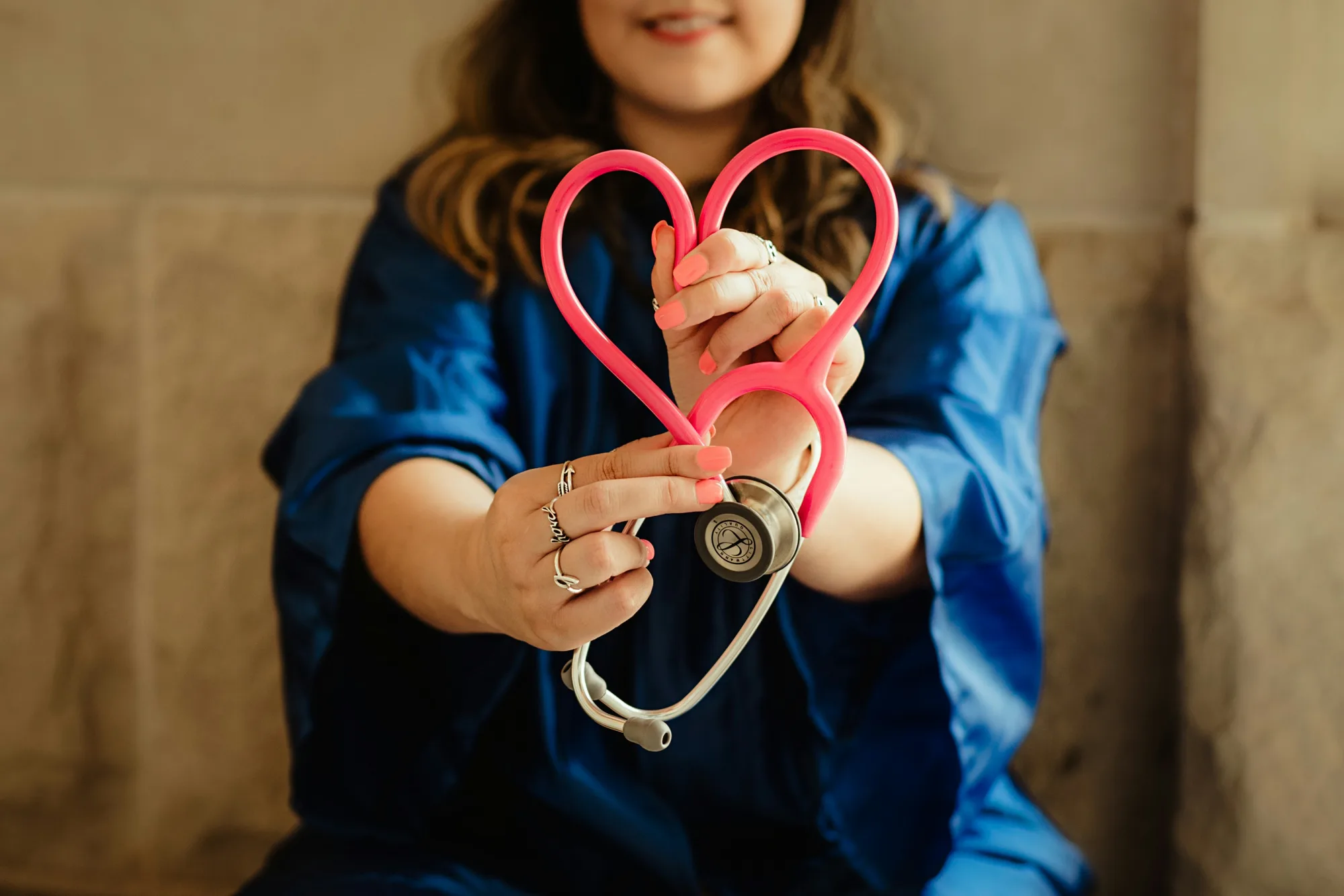 Smiling nurse holding a stethoscope shaped into a heart