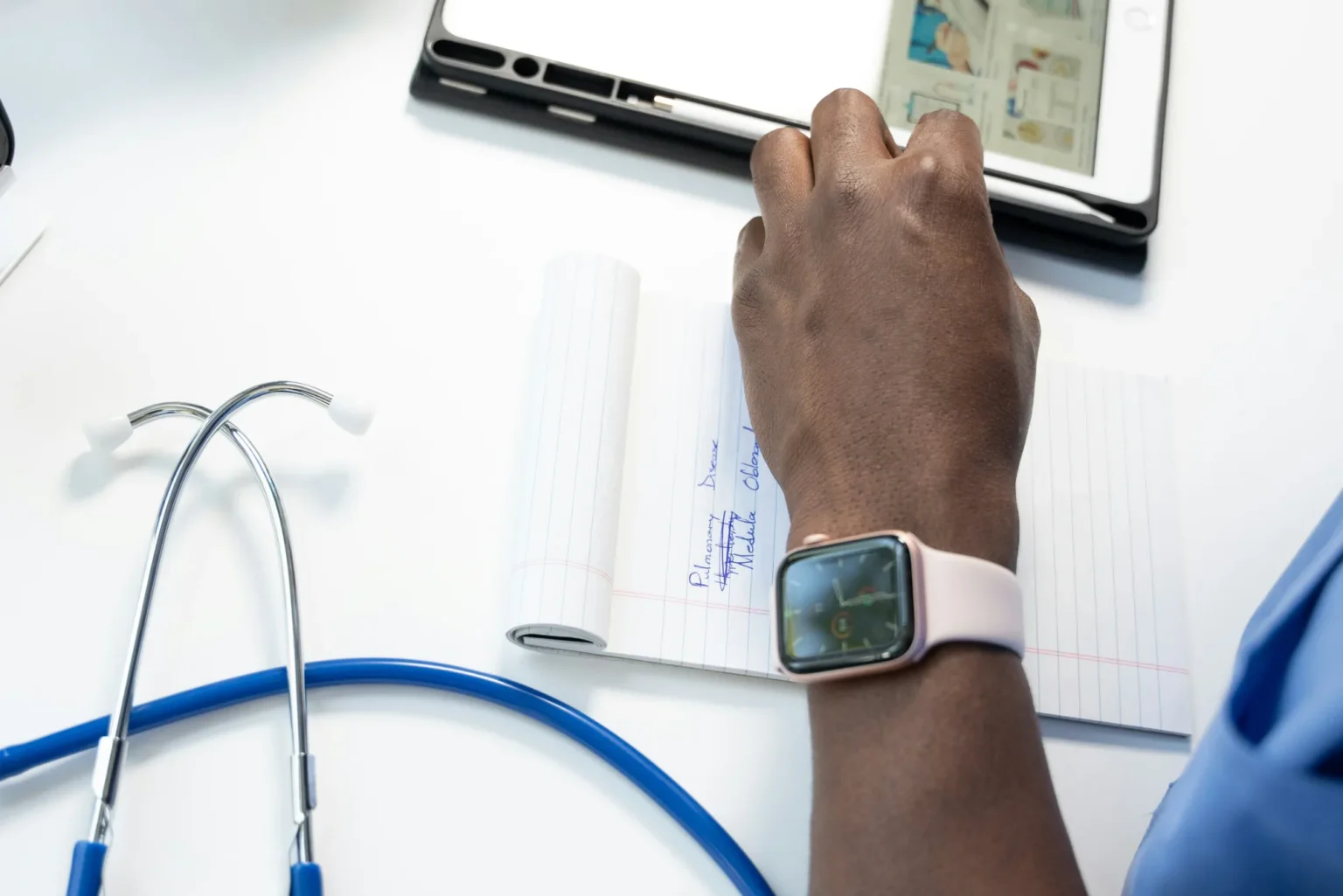 Stethoscope, handwritten clinical notes, and tablet on a desk
